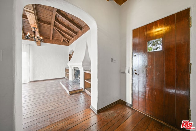 entrance foyer featuring vaulted ceiling with beams, dark wood-type flooring, an inviting chandelier, and wooden ceiling