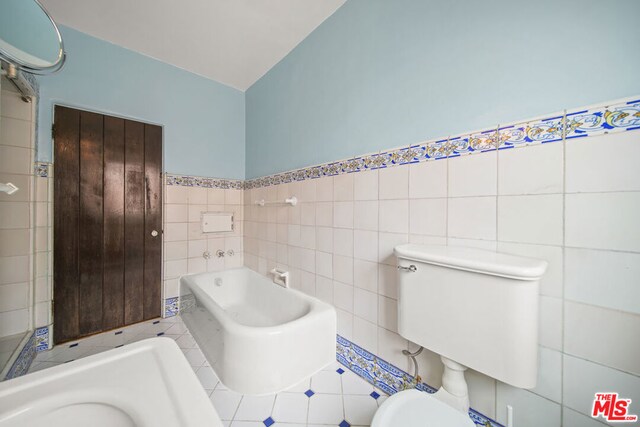 bathroom featuring a washtub, tile walls, and toilet