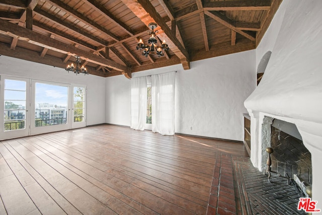 unfurnished living room with hardwood / wood-style floors, an inviting chandelier, lofted ceiling with beams, a brick fireplace, and wood ceiling