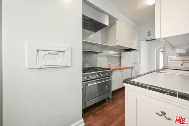 kitchen with high end range, dark hardwood / wood-style floors, white refrigerator, tile countertops, and white cabinets