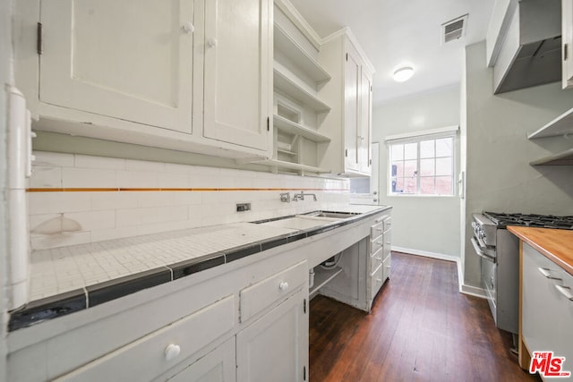 kitchen featuring gas range, white cabinetry, sink, and wood counters