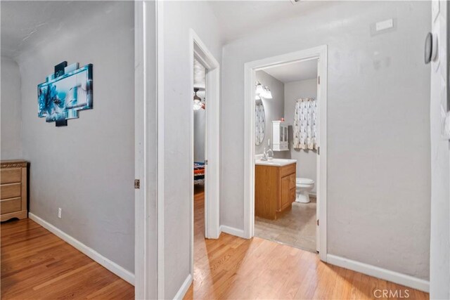 corridor with light hardwood / wood-style flooring and sink