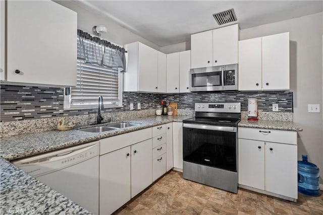 kitchen featuring light stone countertops, sink, tasteful backsplash, white cabinets, and appliances with stainless steel finishes