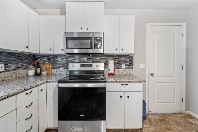 kitchen with white cabinets, appliances with stainless steel finishes, tasteful backsplash, and light stone countertops