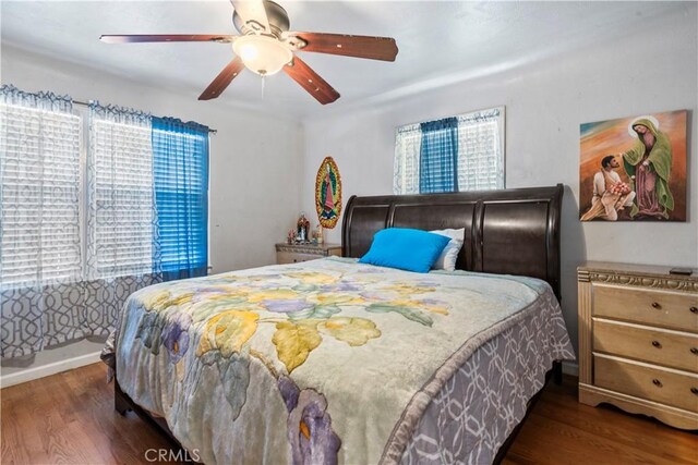 bedroom with ceiling fan, dark hardwood / wood-style flooring, and multiple windows