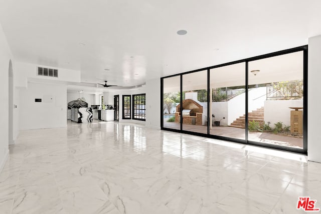 empty room featuring ceiling fan and a wall of windows