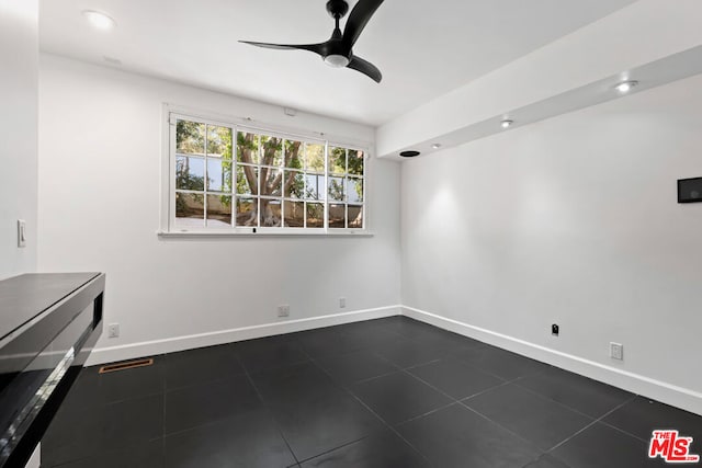 unfurnished room with dark tile patterned floors and ceiling fan