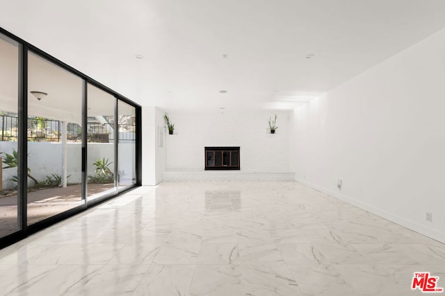 unfurnished living room featuring expansive windows and a brick fireplace