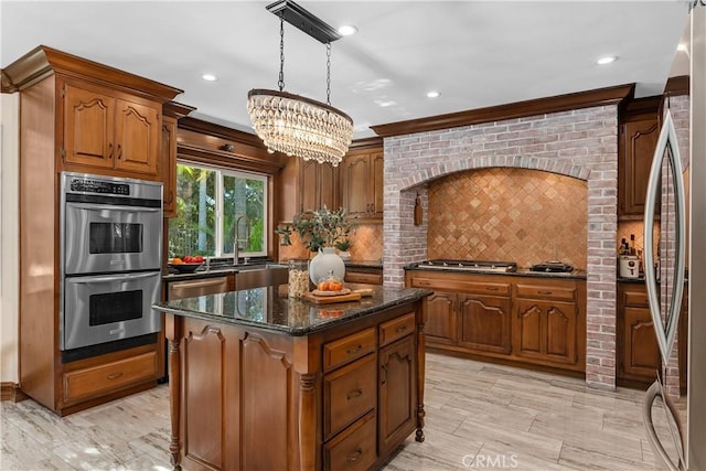 kitchen featuring pendant lighting, backsplash, crown molding, appliances with stainless steel finishes, and a kitchen island