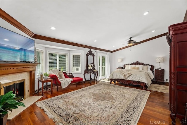 bedroom with crown molding, ceiling fan, dark hardwood / wood-style flooring, and a premium fireplace