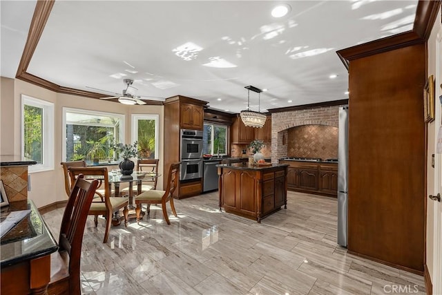 kitchen featuring ceiling fan, tasteful backsplash, pendant lighting, a kitchen island, and appliances with stainless steel finishes