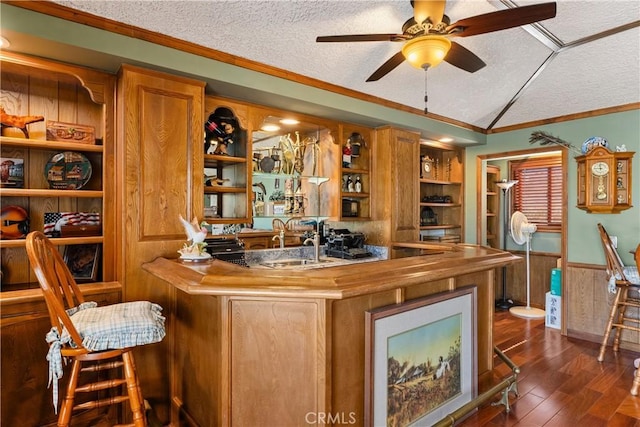 bar with dark wood-type flooring, crown molding, wood walls, a textured ceiling, and vaulted ceiling