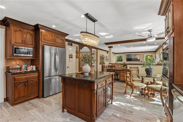 kitchen featuring hanging light fixtures, tasteful backsplash, dark stone counters, a kitchen island, and appliances with stainless steel finishes