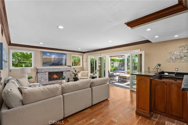 living room with light hardwood / wood-style flooring, a brick fireplace, and crown molding