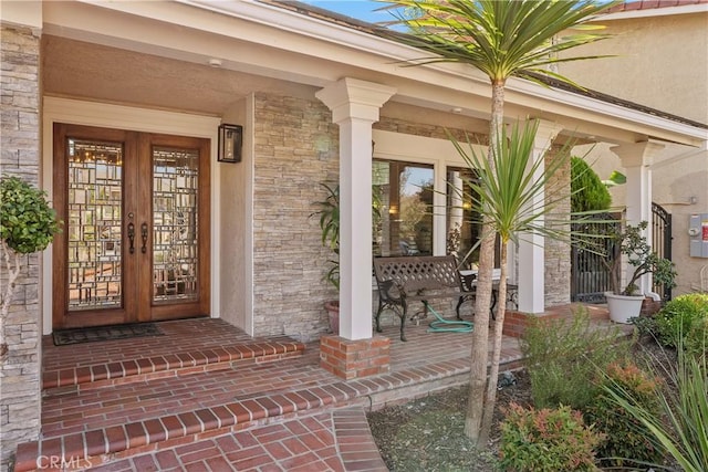 view of exterior entry with covered porch and french doors