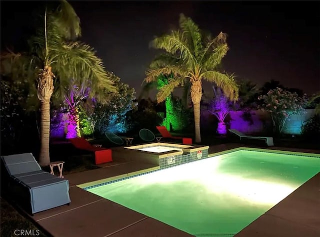 pool at night with an in ground hot tub