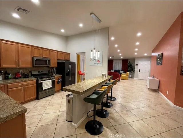 kitchen with backsplash, decorative light fixtures, a kitchen bar, light tile patterned floors, and black appliances