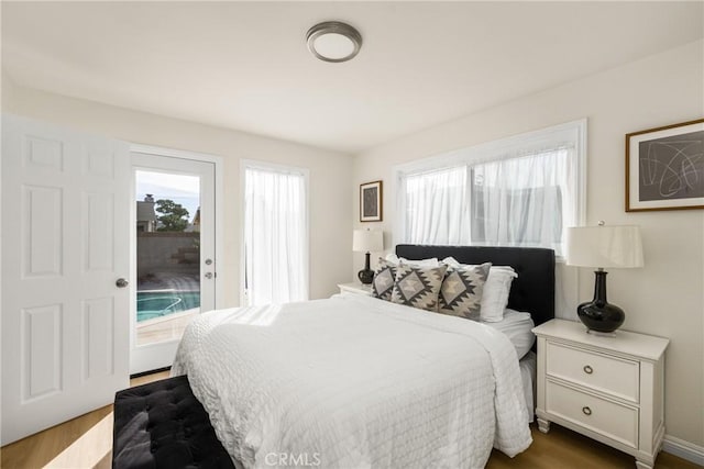 bedroom with access to outside and dark hardwood / wood-style floors