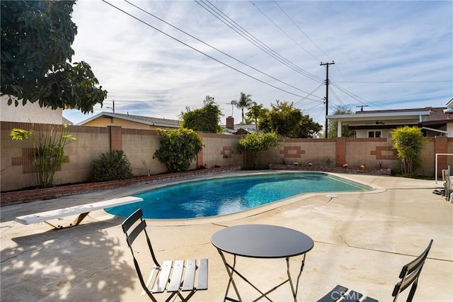 view of pool with a diving board and a patio