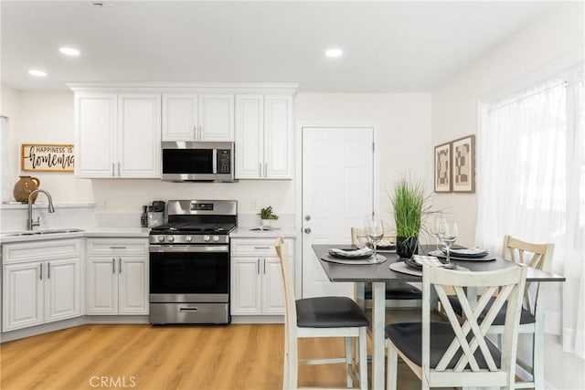 kitchen featuring light hardwood / wood-style floors, sink, white cabinetry, and stainless steel appliances