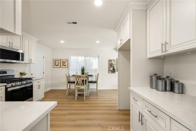 kitchen with white cabinets, stainless steel appliances, and light hardwood / wood-style flooring