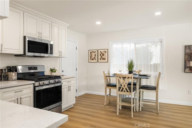 kitchen featuring white cabinets, light wood-type flooring, and stainless steel appliances