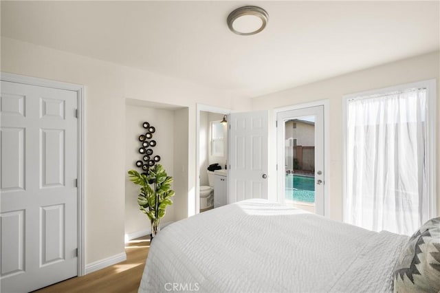 bedroom featuring wood-type flooring, connected bathroom, and multiple windows