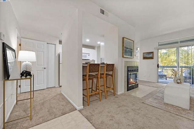 carpeted living room featuring a tiled fireplace