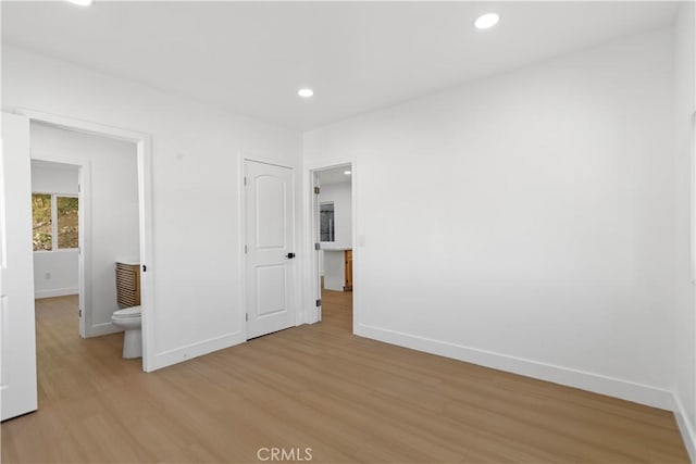 unfurnished bedroom featuring ensuite bath and light hardwood / wood-style flooring