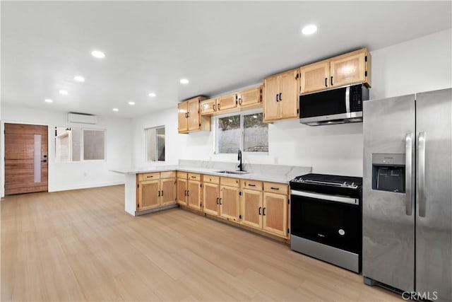 kitchen with a wall mounted AC, sink, light brown cabinetry, appliances with stainless steel finishes, and light hardwood / wood-style floors