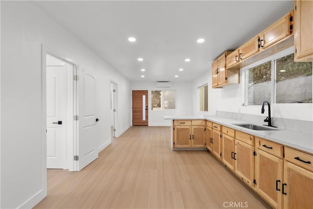 kitchen with sink, light brown cabinets, light hardwood / wood-style flooring, kitchen peninsula, and a wall mounted AC