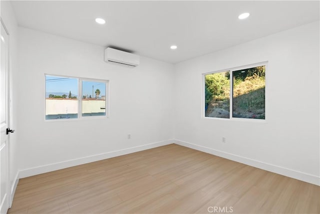 spare room featuring light wood-type flooring and a wall mounted AC