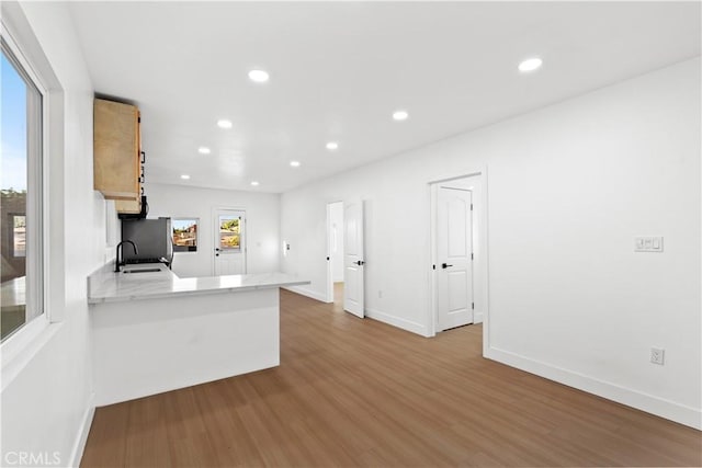 kitchen featuring kitchen peninsula, a wealth of natural light, sink, and light hardwood / wood-style floors