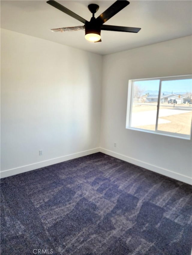 unfurnished room featuring ceiling fan and dark colored carpet