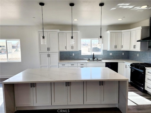 kitchen featuring pendant lighting, black appliances, a kitchen island, sink, and white cabinets