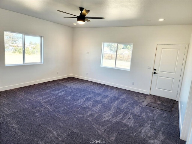 spare room featuring dark colored carpet and ceiling fan