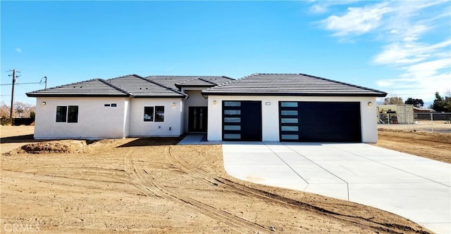 view of front of property with stucco siding, fence, a garage, driveway, and a tiled roof