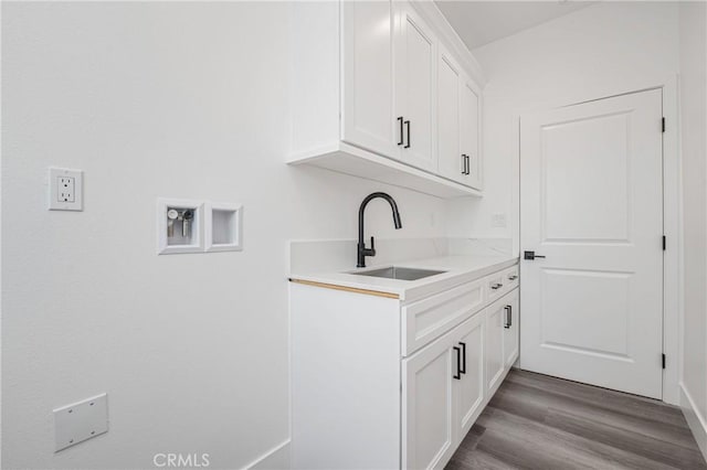 laundry area featuring washer hookup, cabinet space, a sink, and wood finished floors