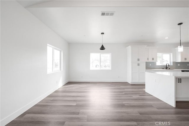 kitchen with wood finished floors, visible vents, white cabinets, light countertops, and tasteful backsplash