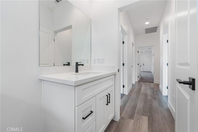 bathroom with recessed lighting, wood finished floors, vanity, visible vents, and baseboards