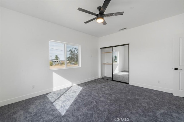 unfurnished bedroom with dark colored carpet, visible vents, and baseboards