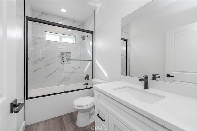 full bath featuring toilet, wood finished floors, combined bath / shower with glass door, vanity, and recessed lighting