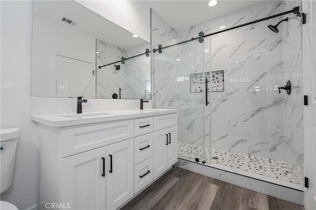 full bathroom with visible vents, wood finished floors, a sink, and toilet