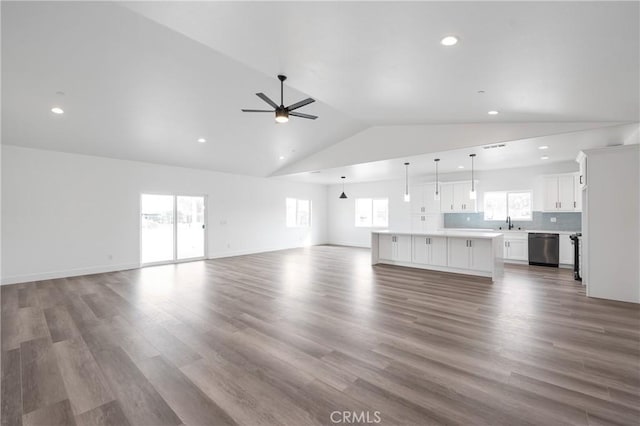 unfurnished living room with ceiling fan, dark wood-style flooring, a sink, baseboards, and vaulted ceiling