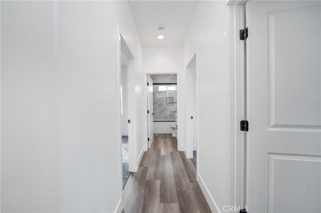 corridor with dark wood-type flooring and baseboards