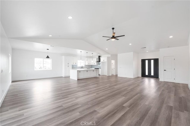 unfurnished living room featuring baseboards, a ceiling fan, wood finished floors, vaulted ceiling, and recessed lighting