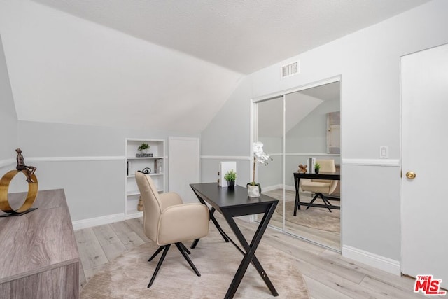 office area with built in shelves, light hardwood / wood-style flooring, and lofted ceiling