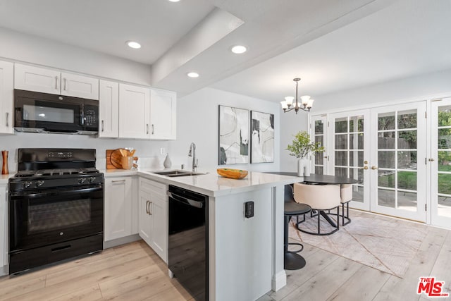 kitchen with kitchen peninsula, a kitchen bar, sink, black appliances, and white cabinetry