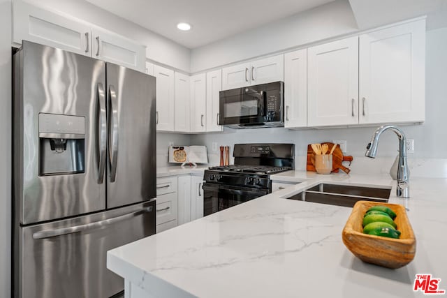 kitchen featuring black appliances, light stone counters, white cabinetry, and sink