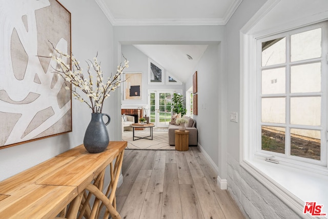 hallway featuring crown molding, light hardwood / wood-style flooring, and lofted ceiling